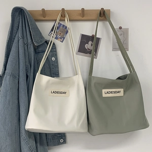 Detail of white and green canvas tote bags with LADIESDAY label on a wooden rack