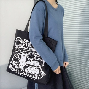 Detail of black canvas tote bag showing white Japanese cartoon illustration and text