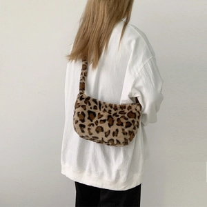 Detailed view of plush leopard print shoulder bag worn by model against white wall