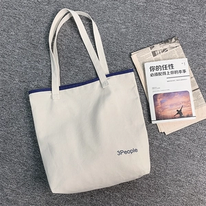 Dettaglio della borsa tote in tela con stampa 3People e bordo blu su tessuto beige