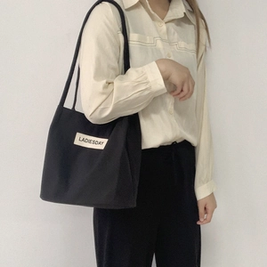 Minimalist black water-resistant nylon tote bag with white LADIESDAY tag and shoulder straps