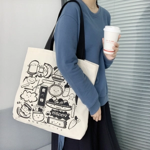 Detail of white canvas tote bag with Japanese food illustrations and black shoulder strap