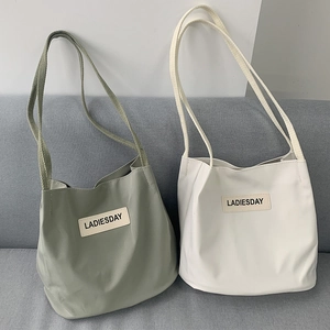 Detail of the soft leather texture and LADIESDAY logo on nylon tote bags in soft colors