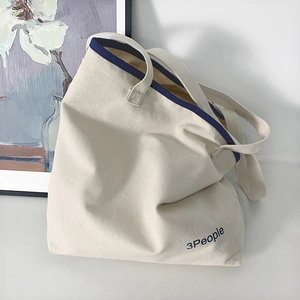 Dettaglio della borsa tote in tela bianco sporco con bordo blu scuro e logo 3People