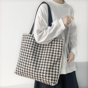 Detail einer klassischen Houndstooth-Einkaufstasche mit schwarzem breitem Schultergurt