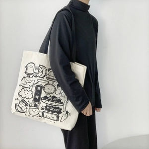 Detail of white canvas tote bag with cute cartoon food illustrations worn by a model