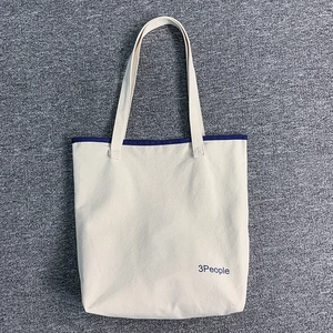 Dettaglio della borsa tote in tela color crema con stampa 3People e bordi blu