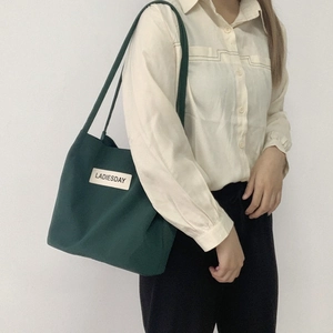 Detail of dark green waterproof nylon tote bag with LADIESDAY label on shoulder