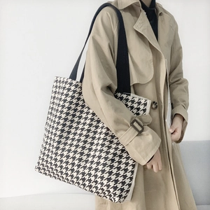 Detail der Textur der schwarz-weißen Hahnentritt-Stofftasche mit schwarzen Riemen