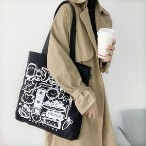 Close-up of black canvas tote bag featuring white cartoon food illustrations and Japanese text