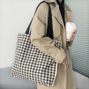 Detailansicht einer großen Tragetasche mit Hahnentrittmuster an einem Model im Trenchcoat