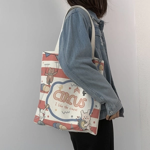 Detailed view of canvas tote bag with circus illustration worn by model on shoulder