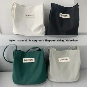 Close-up of waterproof nylon shoulder bags showing fabric texture and leather logo
