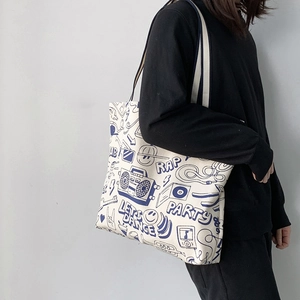 Detail of canvas tote bag showing blue graffiti prints and dual-color shoulder straps
