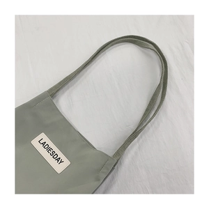 Close-up of waterproof nylon tote bag strap and LADIESDAY logo patch in gray-green