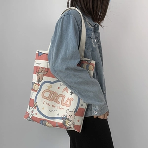 Detail of canvas tote bag featuring circus print and red stripes with shoulder strap