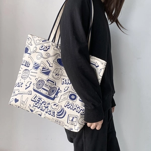 Detail of canvas tote bag with blue retro graffiti and black shoulder straps
