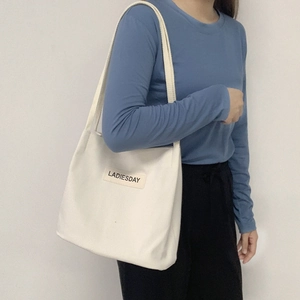 Close-up of a white waterproof nylon canvas tote bag with LADIESDAY leather patch detail