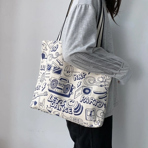 Detail of beige canvas tote bag with blue DJ music prints and striped shoulder strap