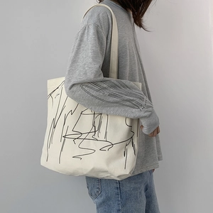 Close-up of minimalist white canvas tote bag with black abstract line art on a model