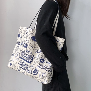 Detail of canvas tote bag featuring navy blue graffiti prints and sturdy handles