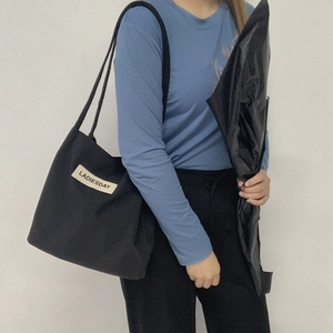 Detail of black nylon tote bag with LADIESDAY patch shown on a shoulder