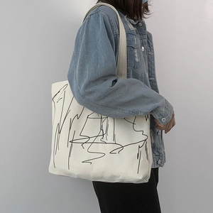 Close-up of a large canvas tote bag featuring black abstract line art for daily use