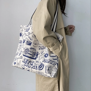 Detail of white canvas tote bag featuring blue street graffiti print and striped straps