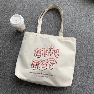 Close-up of cream canvas tote bag with SunSet artistic text and aesthetic quote print