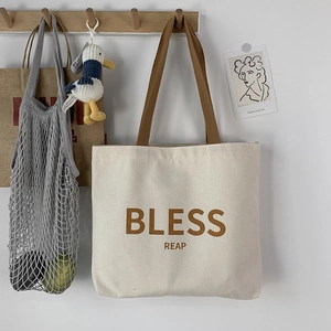 Dettaglio della borsa tote in tela con spalline marroni e stampa BLESS REAP su gancio