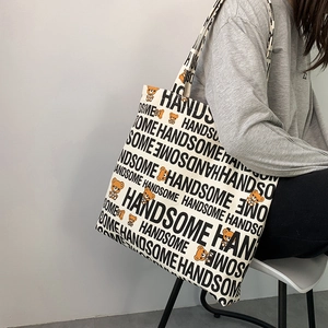 Detail shot of a stylish canvas tote bag featuring bear patterns and HANDSOME lettering