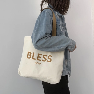 Dettaglio di una borsa tote in tela minimalista con manici marroni e giacca di jeans