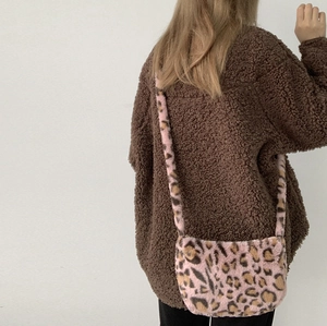 Detail of pink leopard plush crossbody bag worn with brown fleece jacket for autumn style