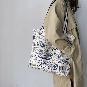 Detail of white canvas tote bag featuring retro graffiti print and striped handles