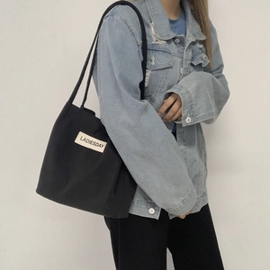 Close-up of black nylon tote bag with white LADIESDAY label on casual denim jacket