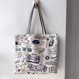 Close-up of canvas tote bag featuring navy blue retro music graffiti on cream fabric