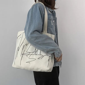 Artistic large canvas tote bag with black abstract lines shown on model shoulder
