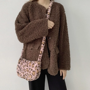 Detailed view of pink leopard print plush crossbody bag paired with brown fleece jacket