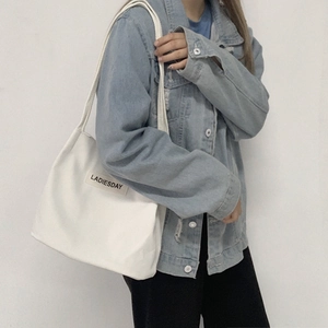 Detailed shot of a large white nylon shoulder bag with LADIESDAY print on a model