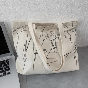 Close-up of minimalist cream canvas tote bag featuring abstract black line art pattern