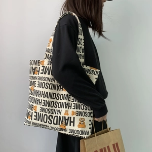 Minimalist canvas tote bag with bear print and Handsome text shown on model shoulder