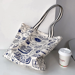 Detail of canvas tote bag with music-themed blue graffiti and striped shoulder strap
