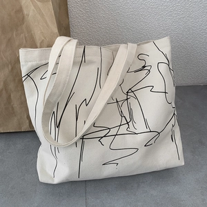 Detail of minimalist canvas tote bag featuring black abstract line art and fabric texture