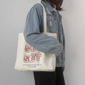 Close-up of white canvas tote bag with artistic SET graphic print and text design