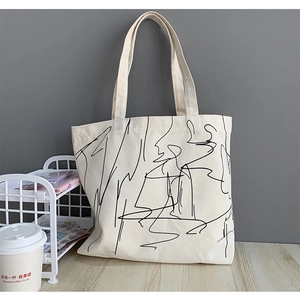 Detail of off-white canvas tote bag with black abstract line art in a minimalist setting