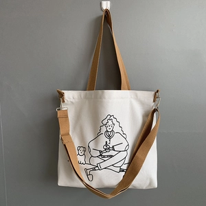 Detail of white canvas tote bag with black minimalist dog illustration and brown straps