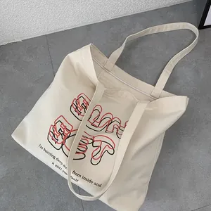 Detail of off-white thick canvas tote bag featuring artistic red and black lettering