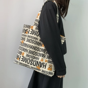 Detail of canvas tote bag featuring HANDSOME lettering and cute orange bear patterns