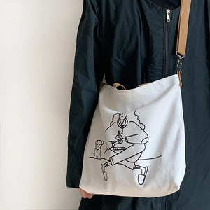 Detailed shot of white canvas crossbody bag with cute cartoon illustration and brown strap