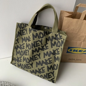 Detail of the thick army green canvas tote bag featuring black MAKE MONEY repetitive print